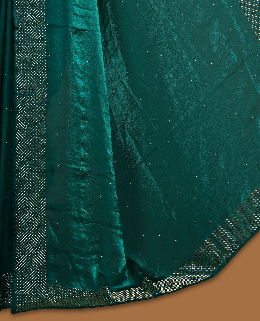 Emerald green chiffon designer saree, featuring dainty scattered stones on the body, enriched with dense stone work and a heavy metallic stone border and pallu, paired with a matching blouse.