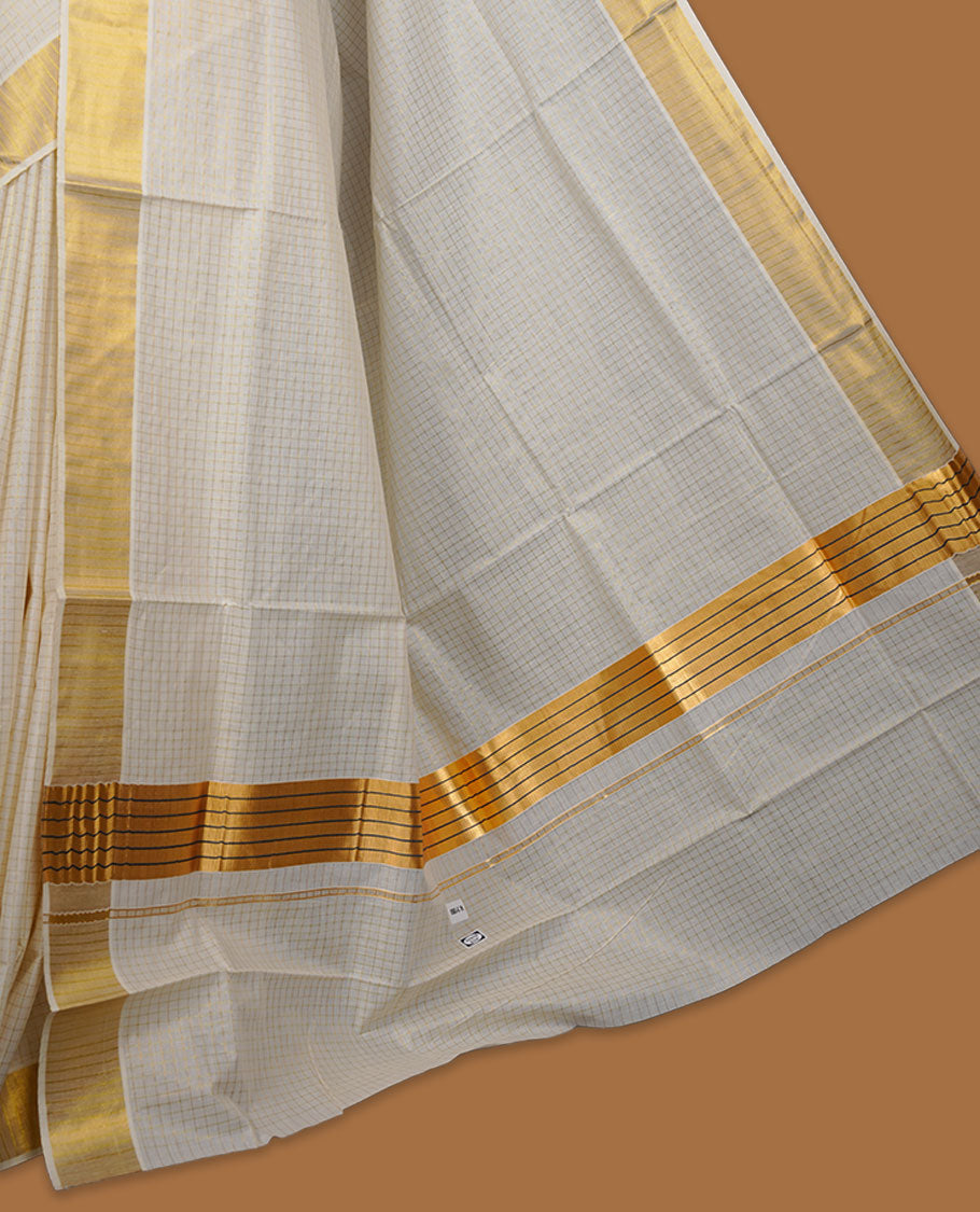 Off-white colour cotton Kerala saree featuring a subtle gold checkered weave, highlighted with a rich traditional gold kasavu border along the pallu and pleats, and paired with a matching blouse.