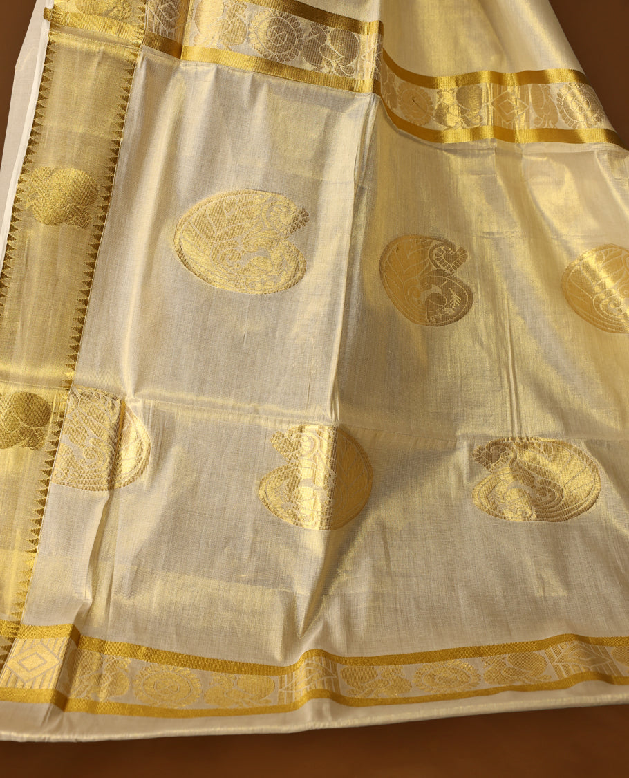 Elegant Light Gold colour Tissue Kerala saree featuring gold zari Chakram motifs on body, traditional golden zari kasavu border & Rich Pallu offering a classic and graceful look, paired with a matching blouse.