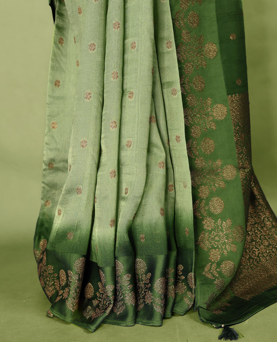 Green double shade semi Banaras Tussar Georgette saree adorned with elegant antique gold zari floral motifs across the body, featuring a detailed woven border and grand pallu, paired with a matching blouse piece.
