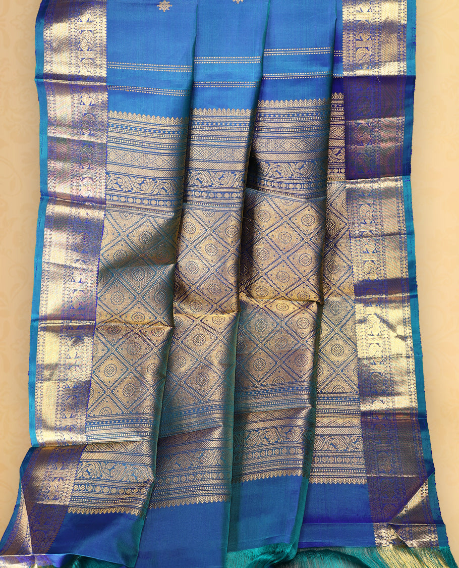 Peacock blue colour pure Kancheepuram saree with gold zari symmetrical motifs, traditional border with peacock and chakra designs, grand pallu with diamond motifs, and matching blouse.