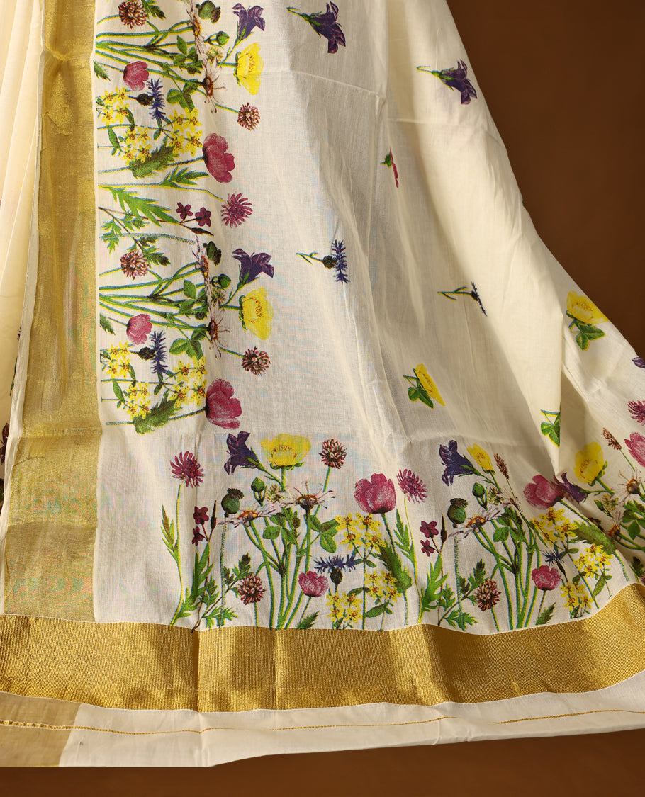 Elegant off white colour cotton Kerala saree with vibrant floral prints and a rich golden zari border, paired with a matching blouse. Perfect for festive occasions and day events with a graceful, natural charm.