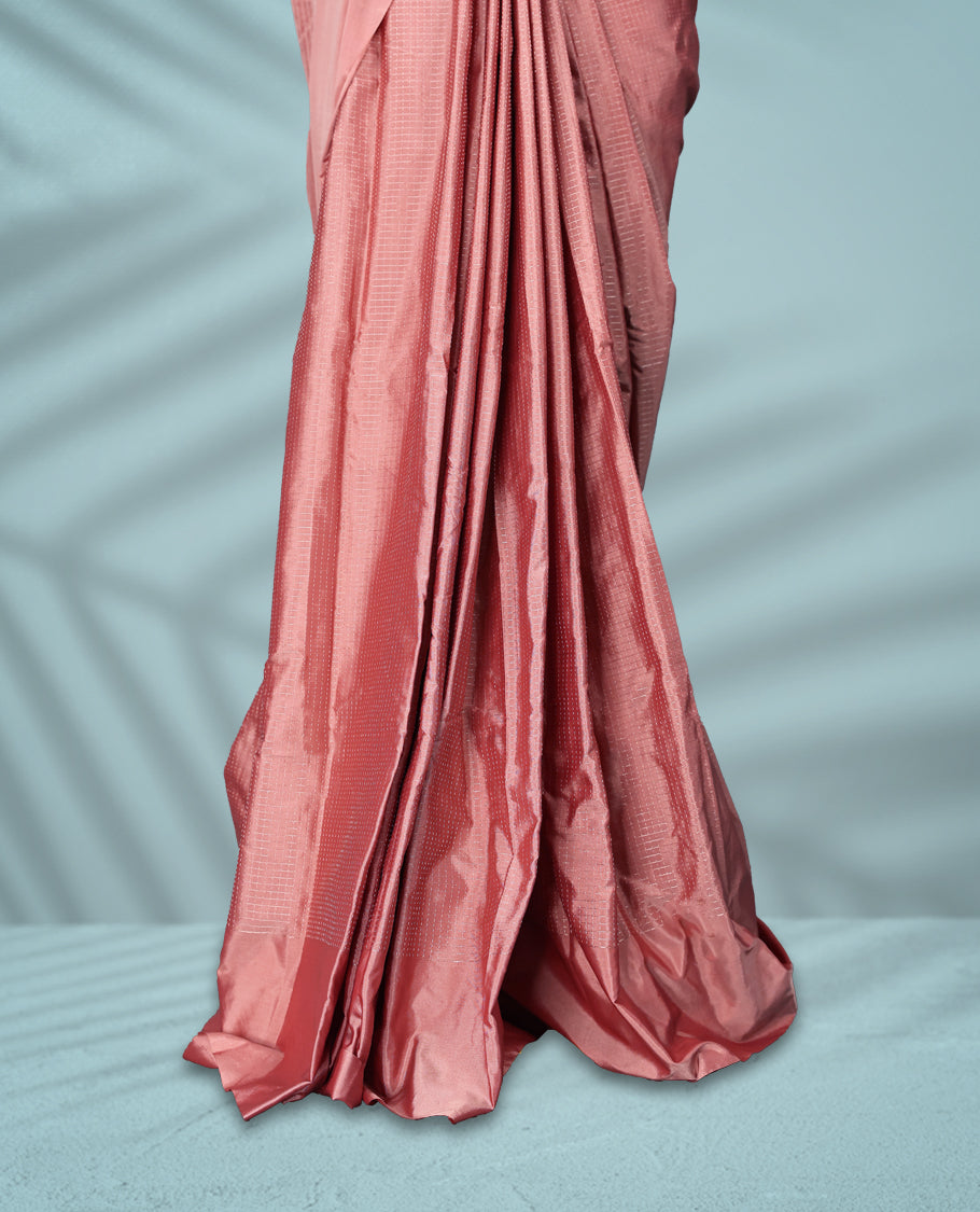 Peach pink colour semi silk saree featuring subtle textured checks on the body, complemented by a self-tone border, and comes with a matching blouse.