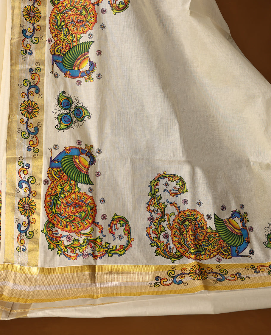 Off white colour Kerala cotton saree featuring vibrant peacock & floral prints, enhanced with a traditional golden kasavu border and A festive ready drape paired with a matching blouse, perfect for graceful celebrations.