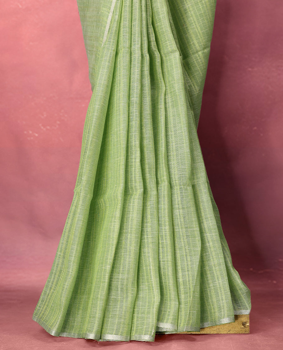 Pastel green colour pure linen saree adorned with delicate stripe patterns all over the body, highlighted with a simple white border and comes with a matching blouse