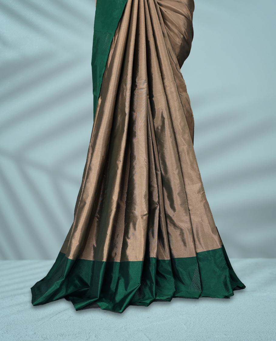 Taupe colour semi silk saree adorned with minimal geometric weave detailing, enhanced by a deep emerald green border, comes with a matching blouse.