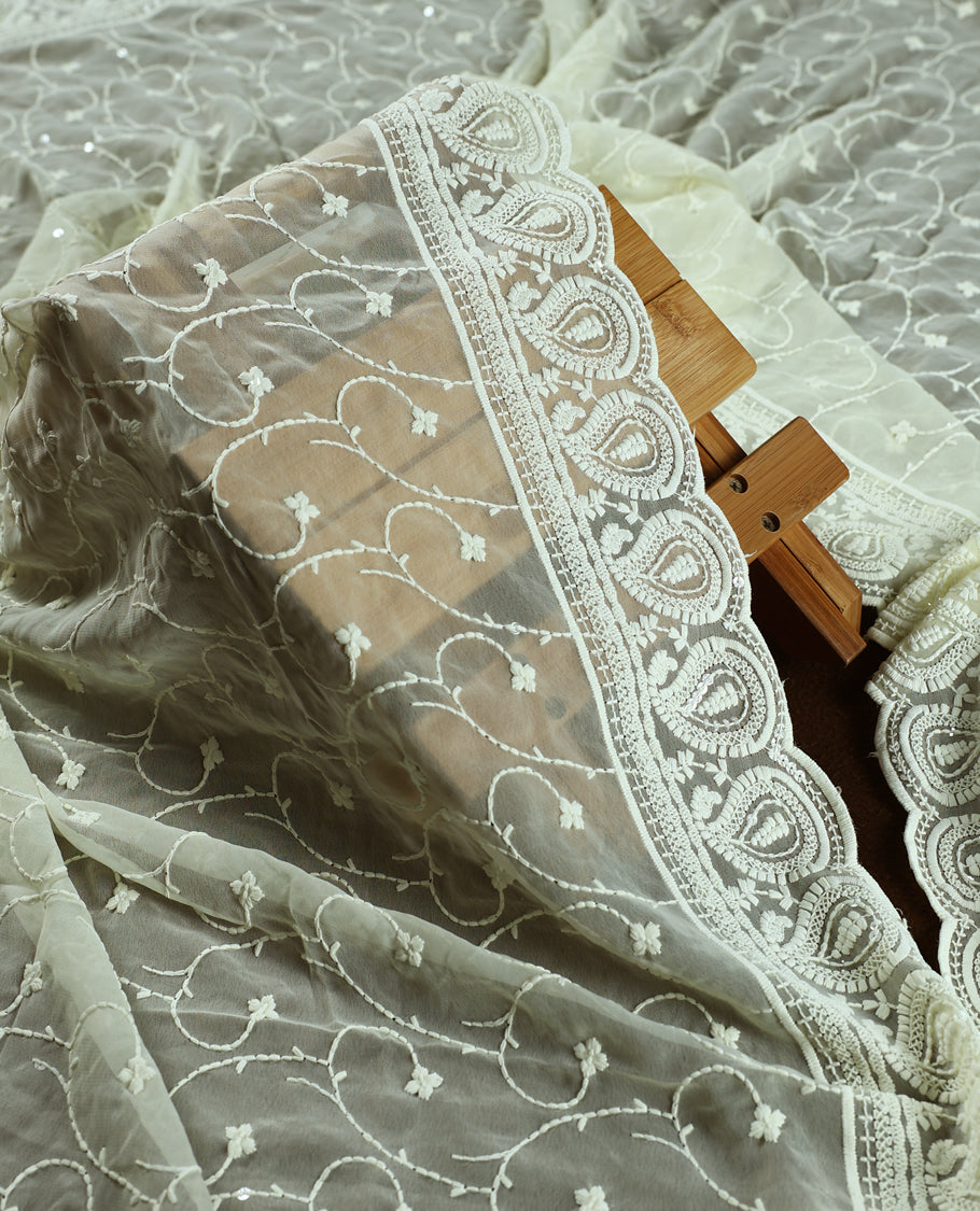 Cream colour churidhar material with embroidered yellow colour neck work, white thread floral motifs on the body, and multicolor floral detailing in yellow, orange, green  & Comes with plain bottom and embroidered dupatta