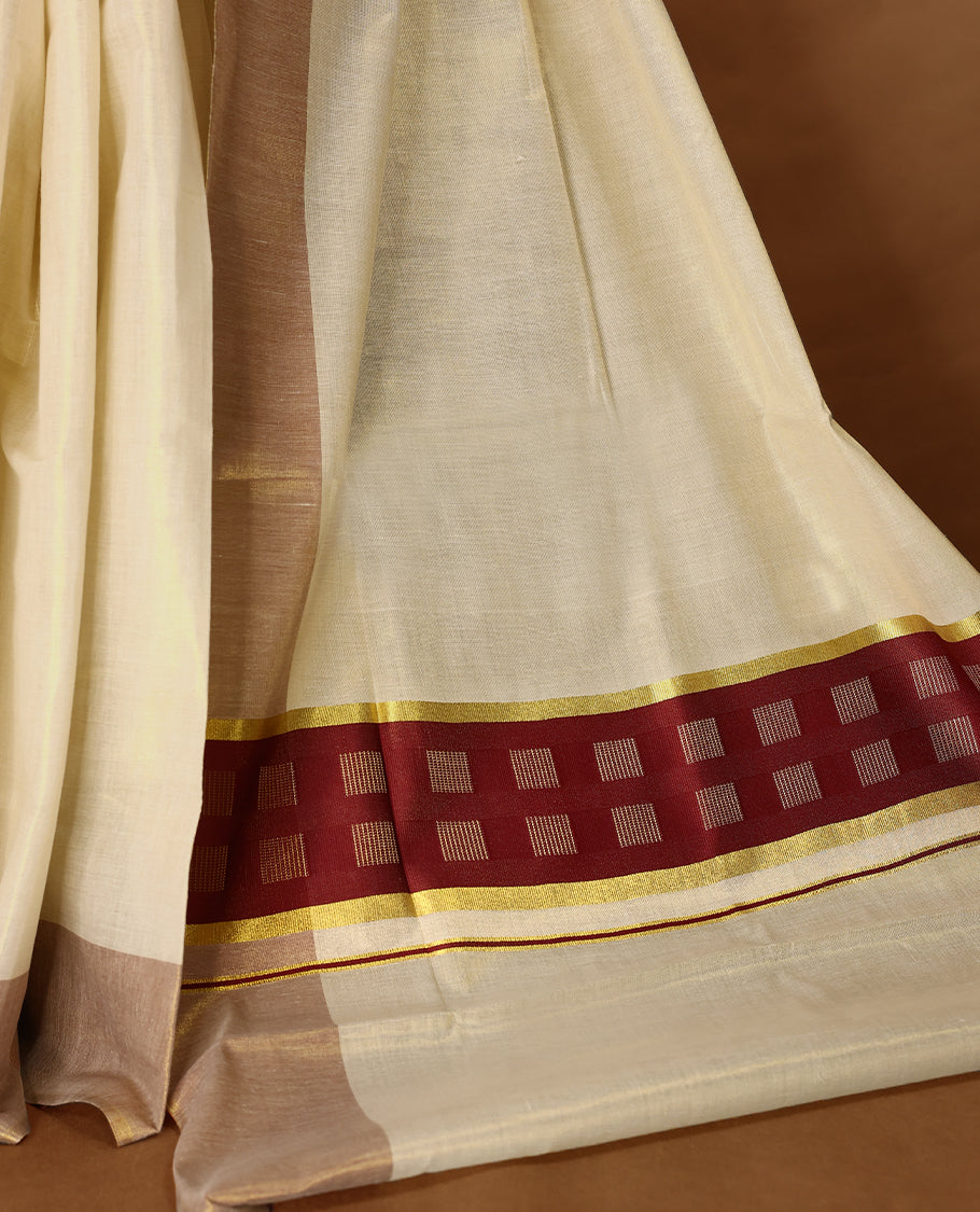 Elegant light gold Colour soft tissue Kerala saree featuring a plain body, muted Red zari border, and a striking Maroon woven checkered pallu, paired with a matching blouse.