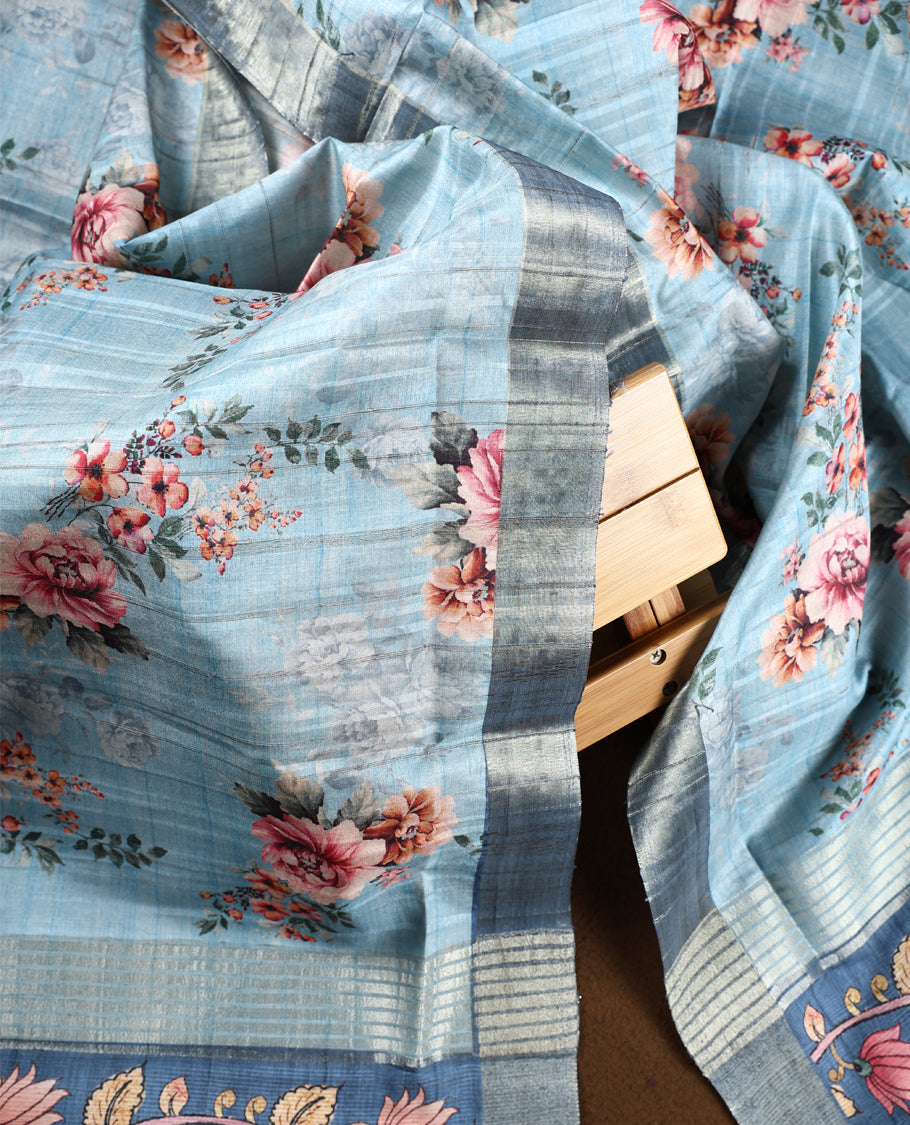 Dark pastel blue colour churidhar material adorned with floral embroidery and sewn glass beads on the yoke, paired with a plain blue bottom and a beige dupatta featuring floral prints.
