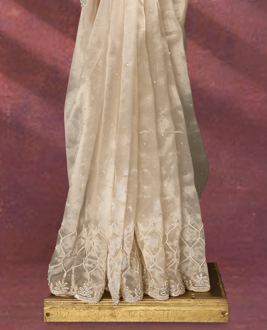 Beige colour pure organza saree featuring sequin work all over the body, adorned with a heavily embellished border with beads, stones, and sequins, complemented by a worked pallu and paired with a matching embellished blouse
