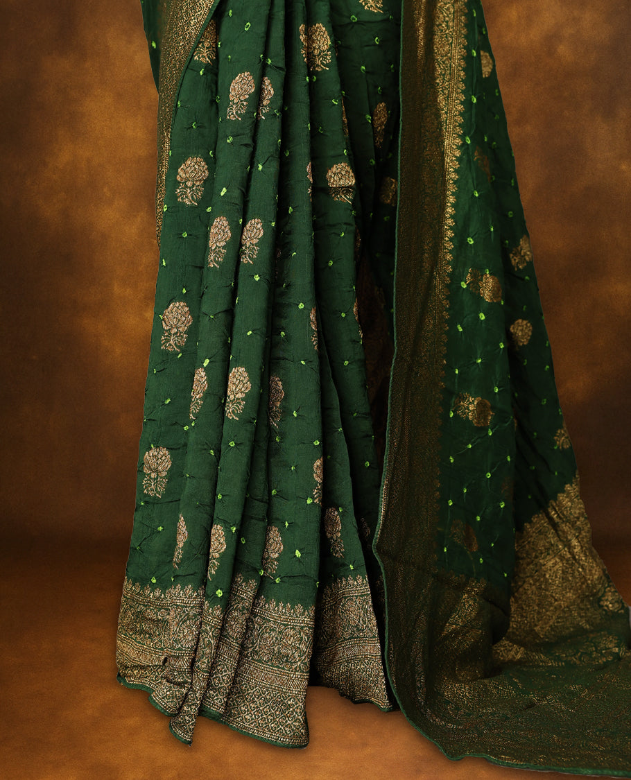 Deep green colour Banarasi Bandhani silk saree featuring light parrot green hand Bandhani patterns with intricate Banarasi motifs, complemented by antique zari woven border and grand pallu, paired with matching antique zari brocade blouse.