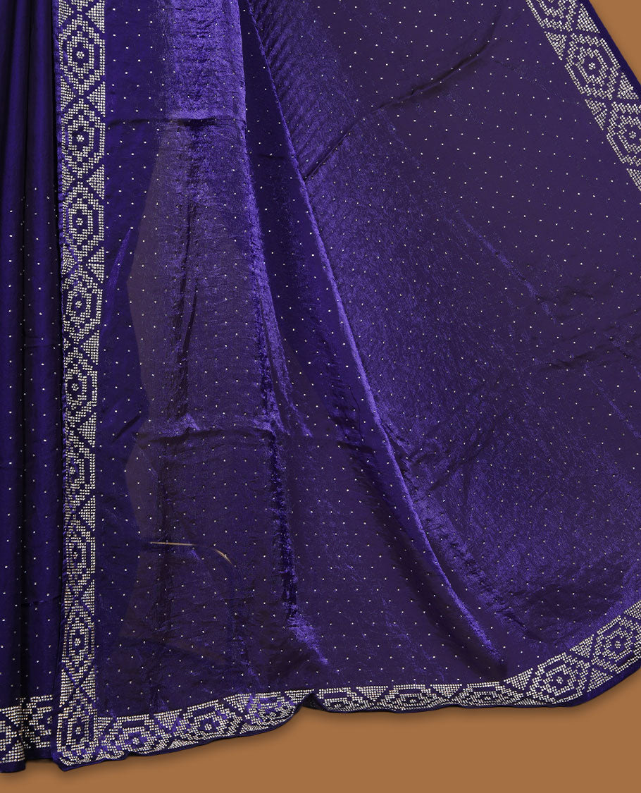 Dark violet colour chiffon designer saree, featuring delicate scattered stone detailing all over the body, highlighted with intricate stone work and a heavy geometric stone pattern along the border and pallu, paired with a matching embellished blouse.a