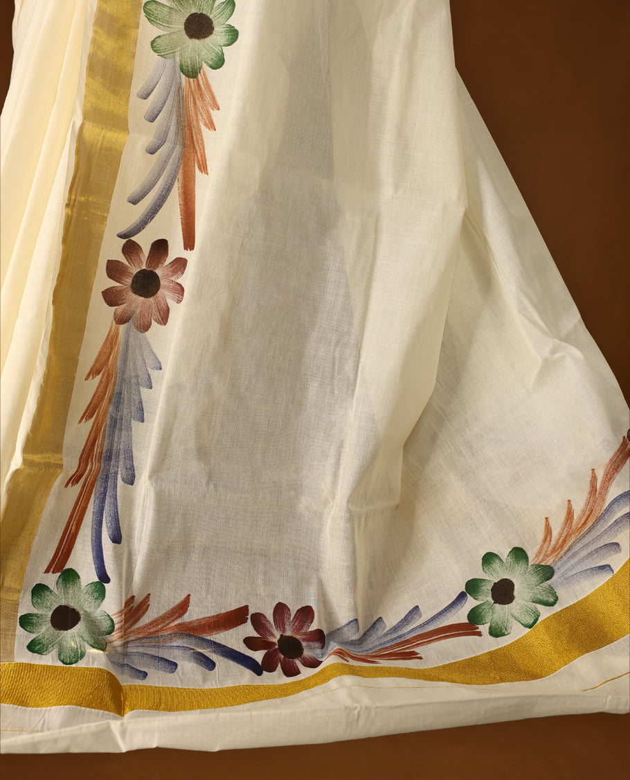 Elegant Off White Colour Kerala Cotton Saree adorned with hand painted floral motifs in earthy tones,Highlighted with a classic Gold Kasavu border and matching blouse, perfect for festive and traditional occasions.