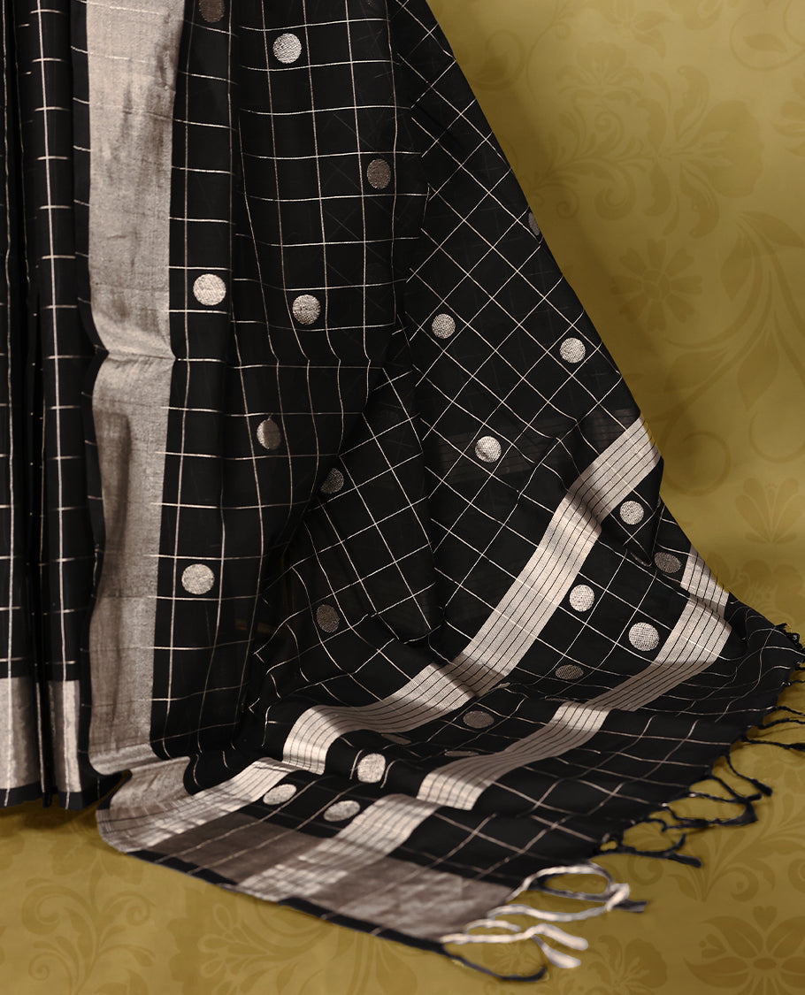Black colour pure handloom cotton kerala saree with white checkered pattern and silver woven buttas on the body, silver zari border, pallu detailed with silver zari stripes and buttas, with matching blouse