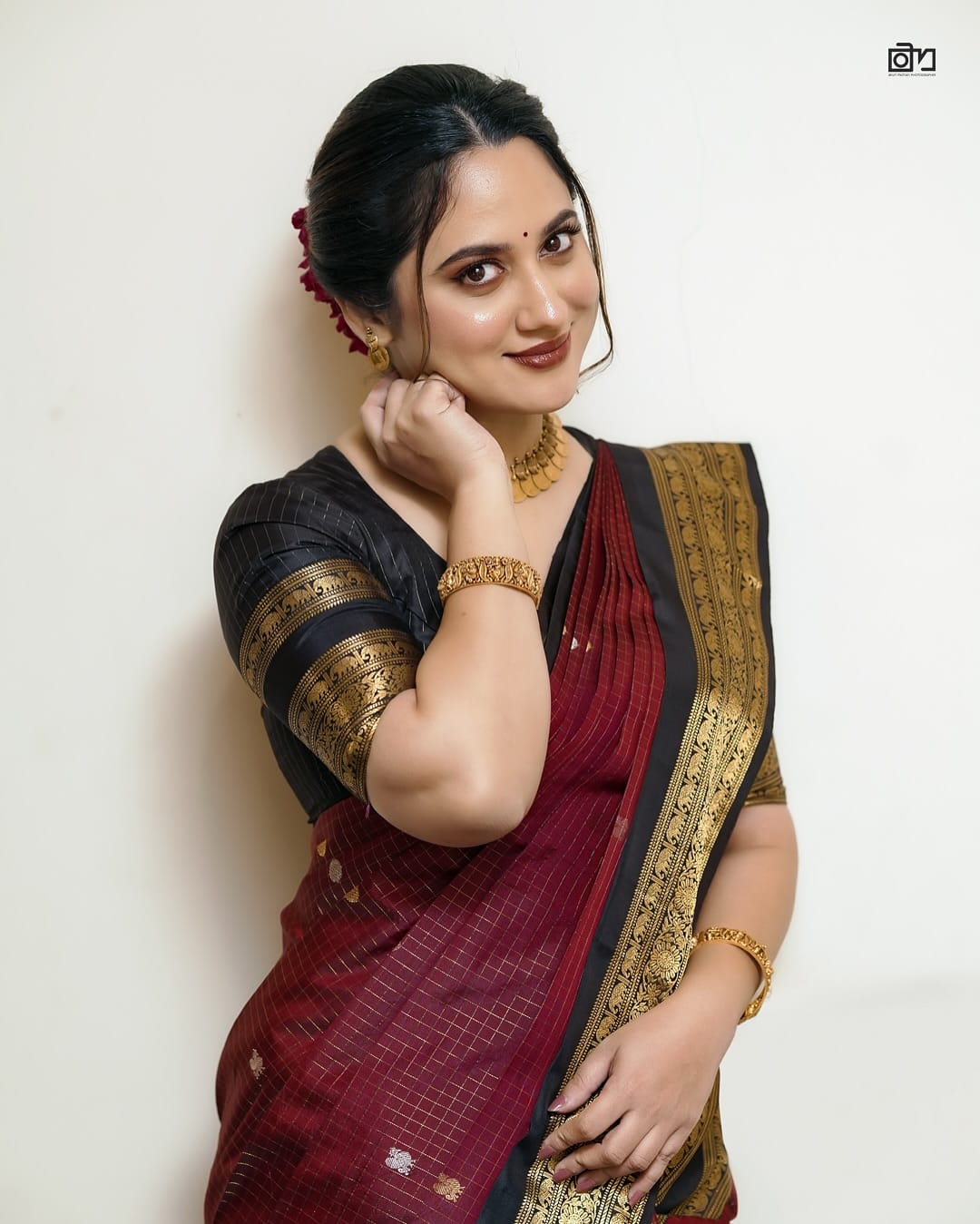 Elegant black and maroon pure Kancheepuram silk saree featuring gold zari elephant & floral brocade border rich maroon body with gold checkered patterns and Gold & Silver colour Peacock Motifs, traditional pallu paired with matching blouse