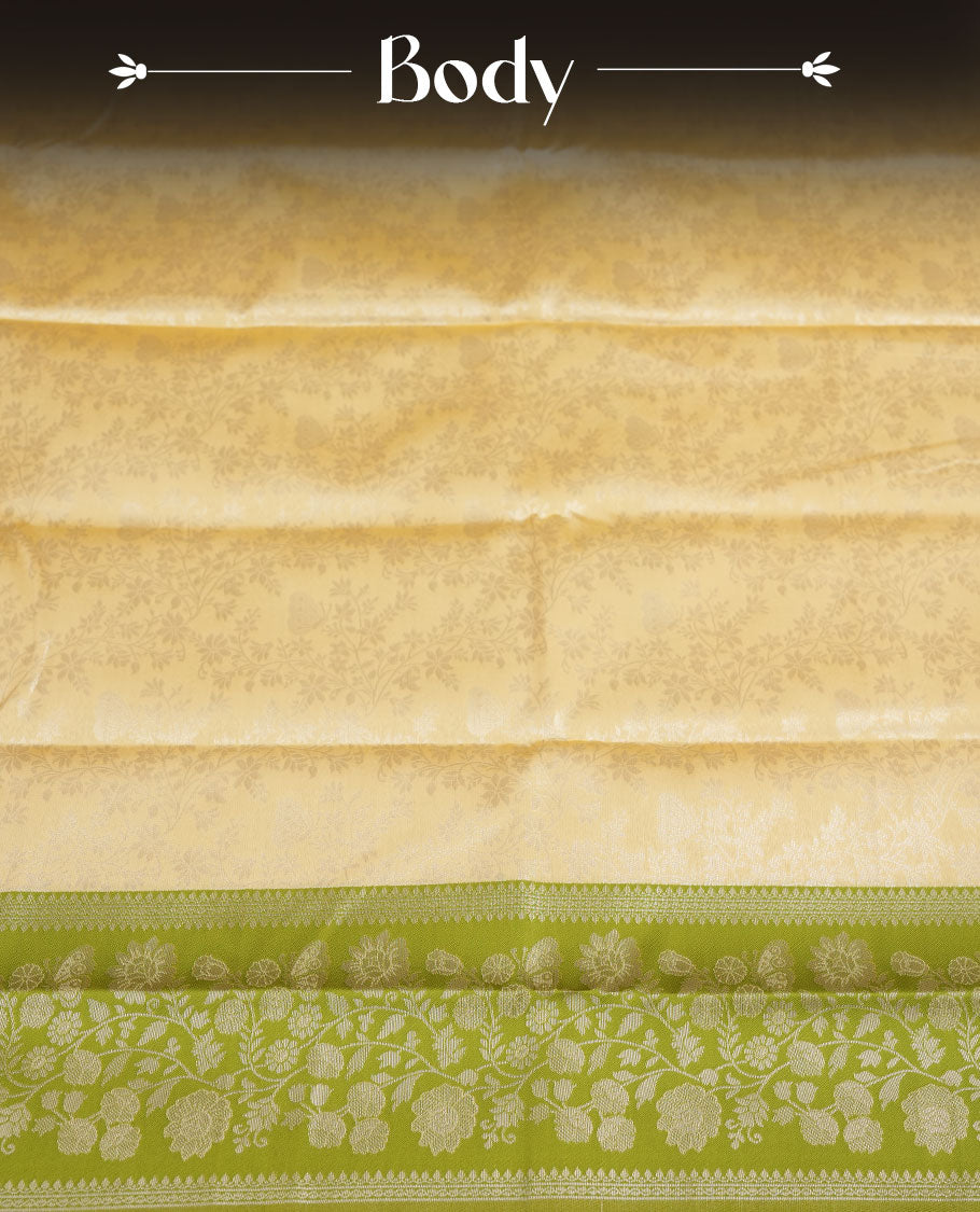Light cream colour semi silk saree adorned with delicate golden zari buttas across the body, complemented by an elegant olive green pallu and matching border, and paired with a coordinated blouse piece