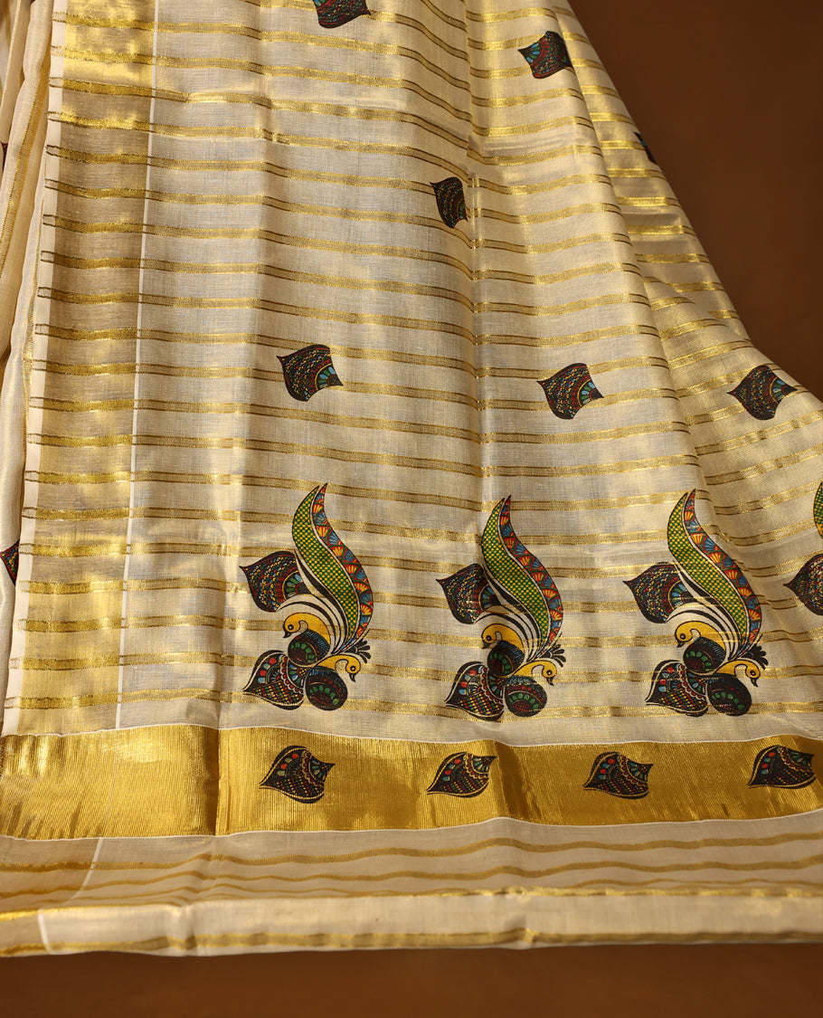 Elegant off white colour tissue Kerala saree featuring golden zari stripes, adorned with vibrant multicolour paisley motifs, and finished with a shimmering gold border and pallu & Paired with a matching blouse.