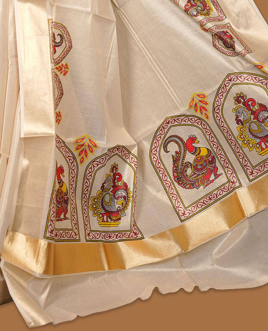 Off-white colour tissue Kerala saree, featuring a rich gold kasavu border and traditional Kalamkari-inspired peacock and elephant motifs across the body and pallu. Lightweight, breathable, and paired with a matching blouse.