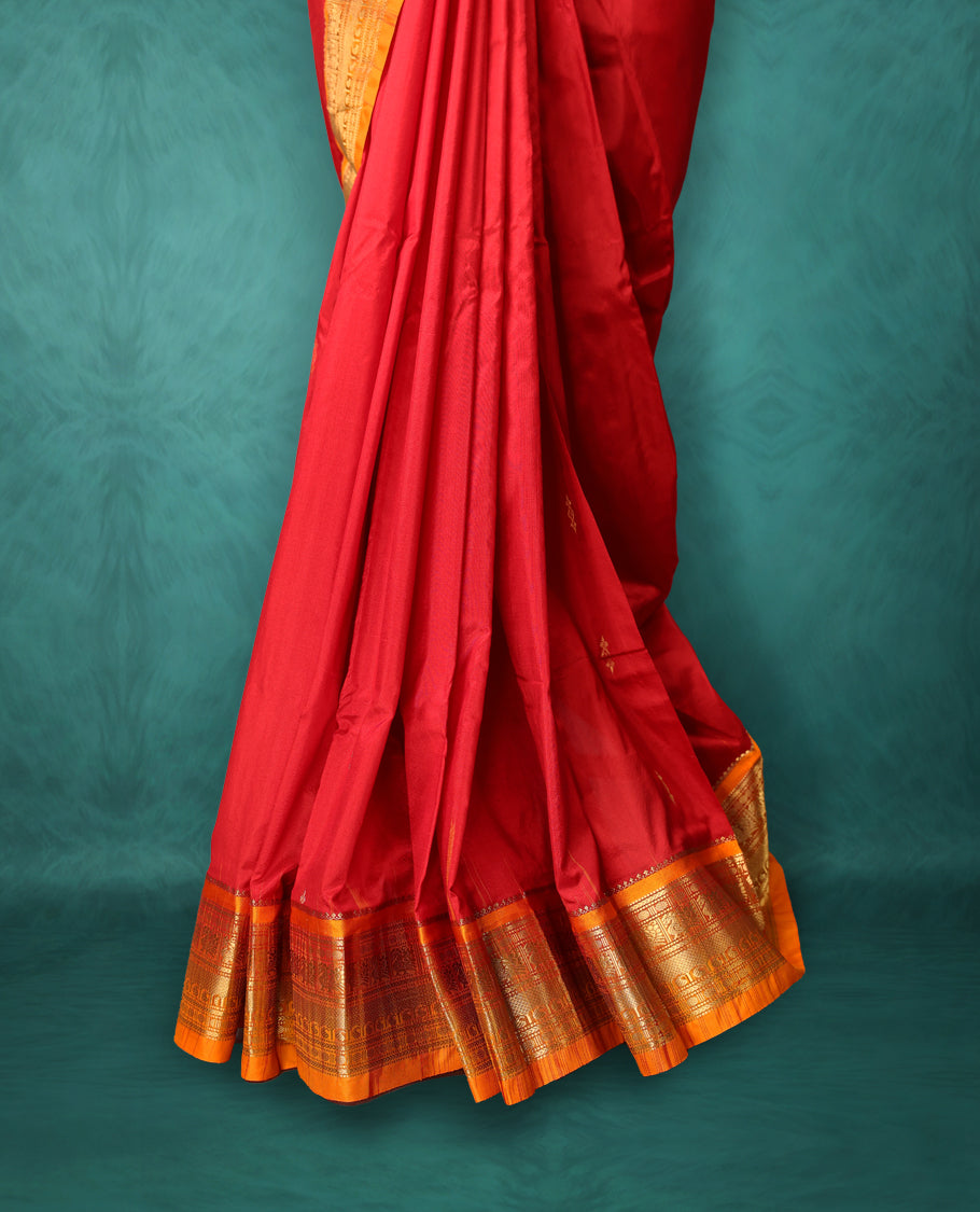 Deep Red colour Traditional Kancheepuram Silk saree with small gold motifs on body, orange colour traditional border with intricate gold zari weaving, grand zari pallu, perfect for Bharatanatyam, with matching blouse.