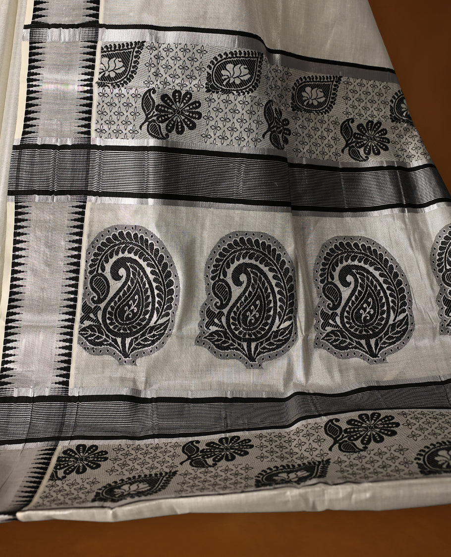 Elegant Tissue Kerala saree in off white colour featuring bold black paisley & floral motifs, woven on a sleek striped body with a striking black kasavu border and Paired with a matching blouse, perfect for festivities.