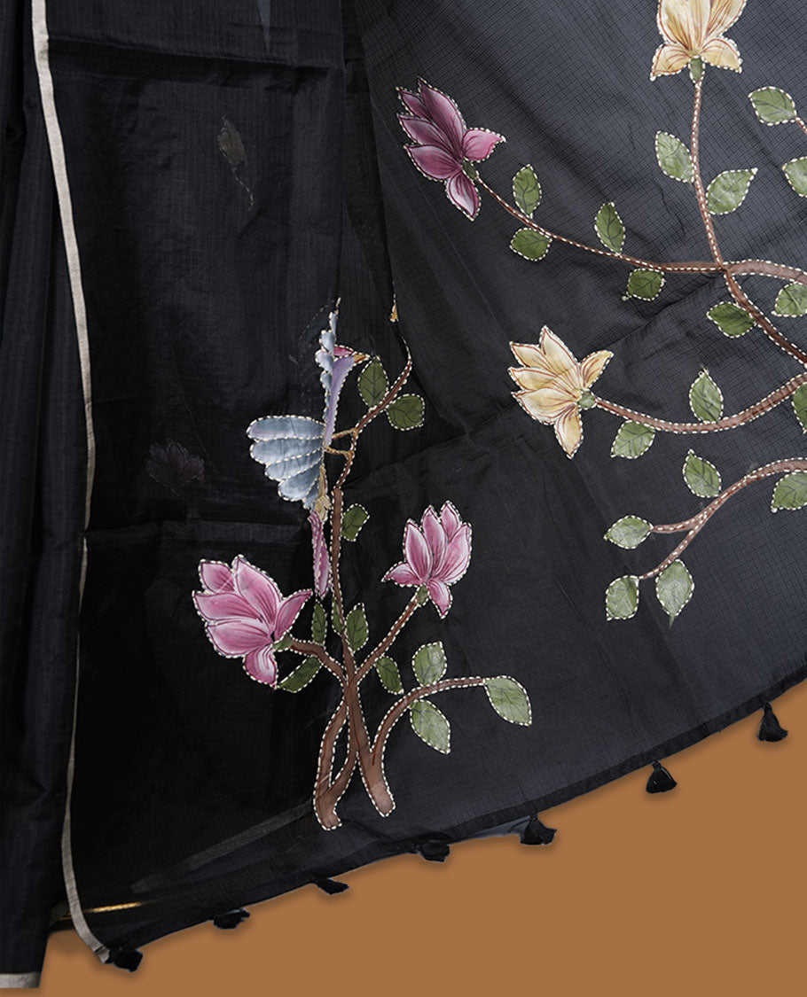 Black colour semi tusser silk saree featuring delicate floral embroidery motifs across the body with subtle contrast detailing on the border, paired with a matching embroidered blouse.