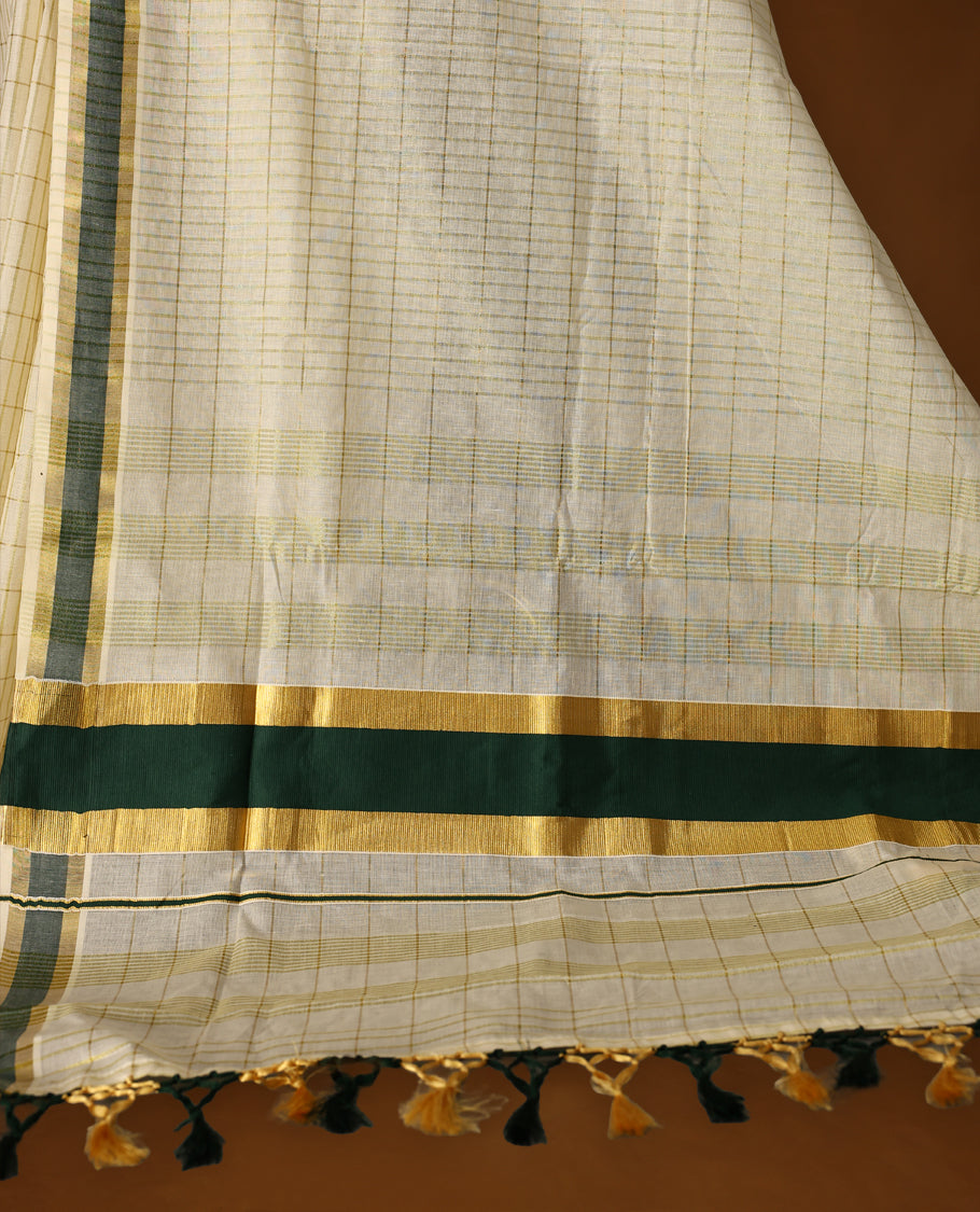 Elegant off white colour cotton Kerala saree featuring subtle golden checks, green & gold zari border, and rich striped pallu with tassels, offering a classic, graceful look &Pair with a matching blouse for charm.