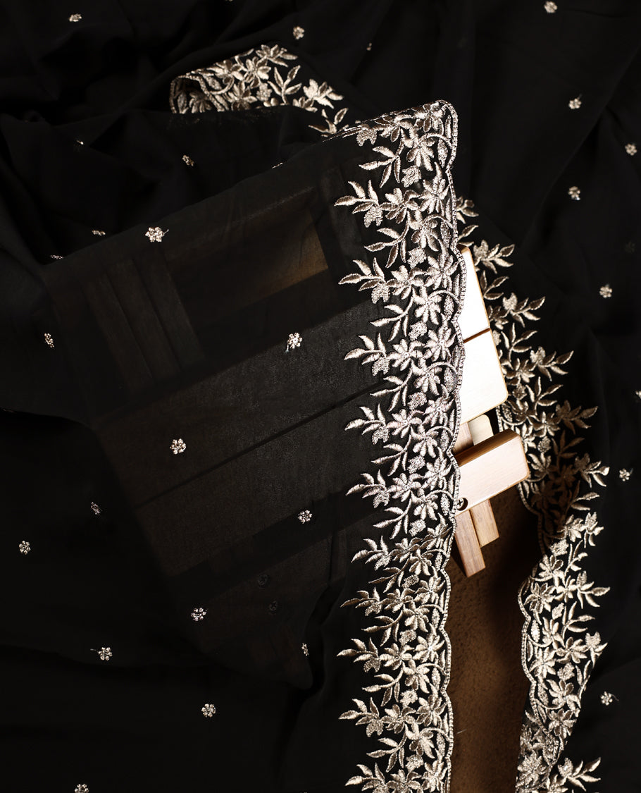 Black colour churidhar material beautifully designed with golden floral embroidery, thread highlights, paired with a plain matching bottom and an elegant embroidered dupatta.