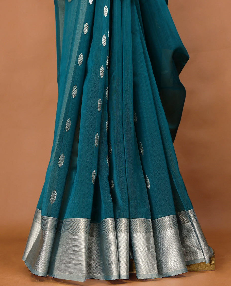 Peacock Blue coloured Maheshwari Cotton saree featuring Silver Zari motifs across the entire body, complemented by a traditional White coloured border and a matching blouse.