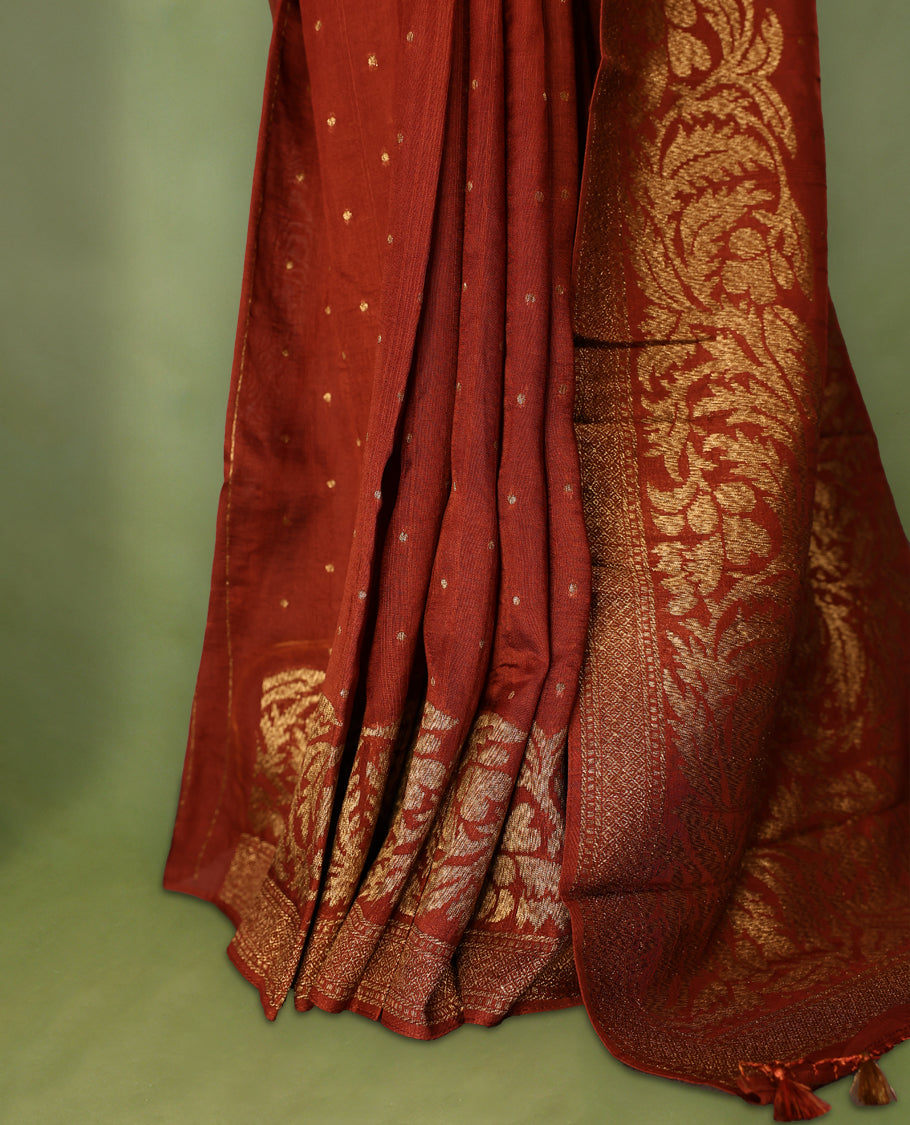 Rust Orange colour Tussar Banaras saree adorned with delicate golden zari motifs on the body, rich floral woven zari border and grand pallu, paired with a matching blouse for an elegant and regal traditional look.