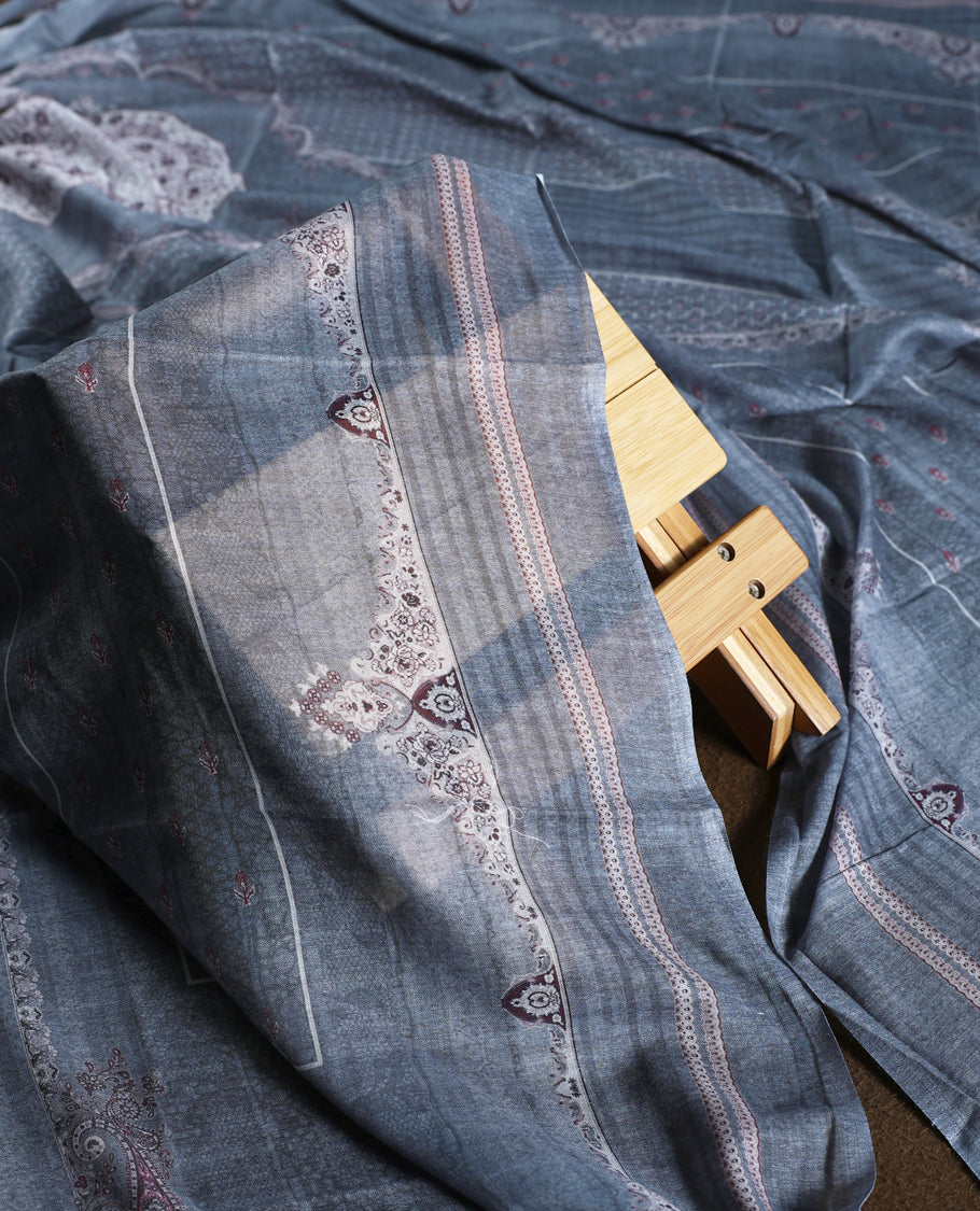 Denim blue colour churidhar material with intricate white and silver embroidery on the neckline, paired with a coordinated printed dupatta and plain bottom.