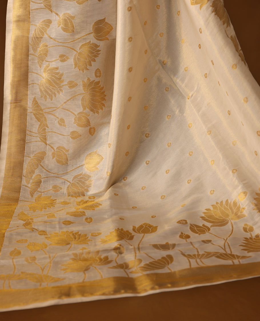 Elegant off white colour soft tissue Kerala saree with golden floral weaving and zari border, Lightweight and sheer, paired with a matching blouse & ideal for festive and traditional occasions.