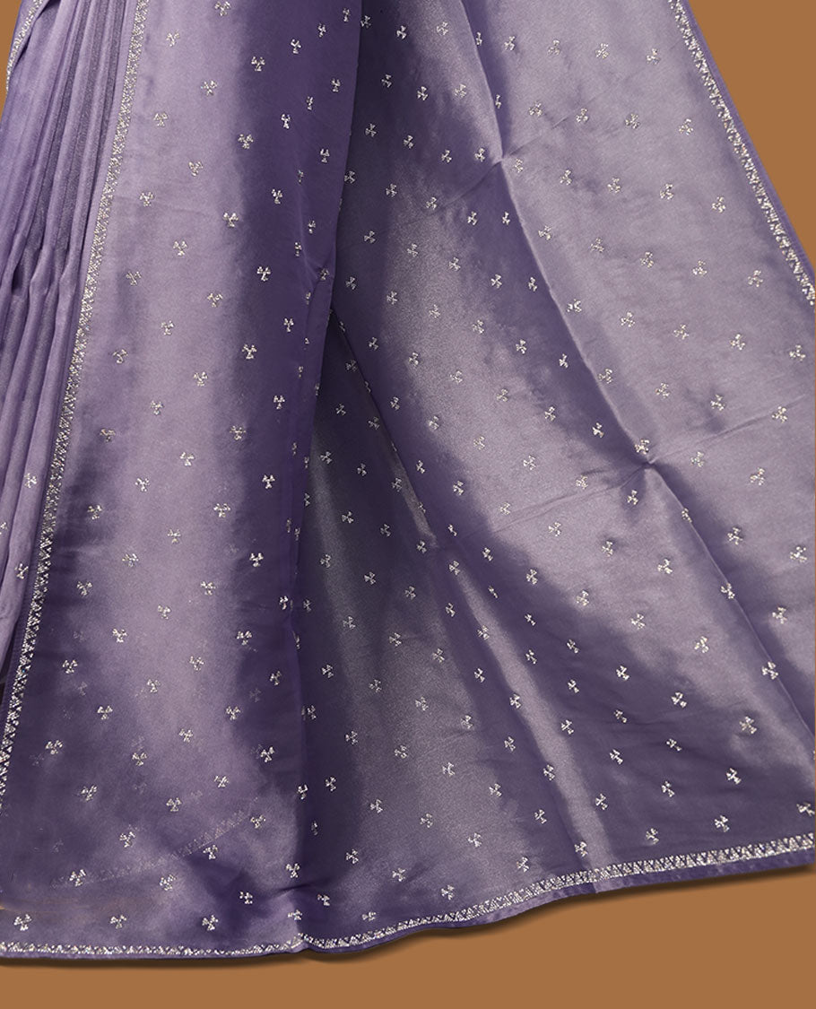 Lavender colour net shimmer fancy saree adorned with scattered white stone buttas all over the body, paired with a delicate stone worked border and matching blouse featuring floral vine stone embroidery