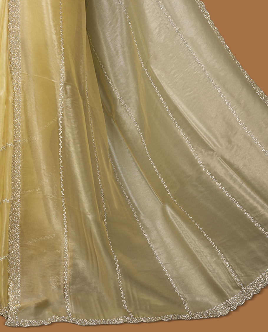 Pale yellow colour net shimmer fancy saree adorned with scattered white stone buttas all over the body, paired with a delicate stone worked border and matching blouse.