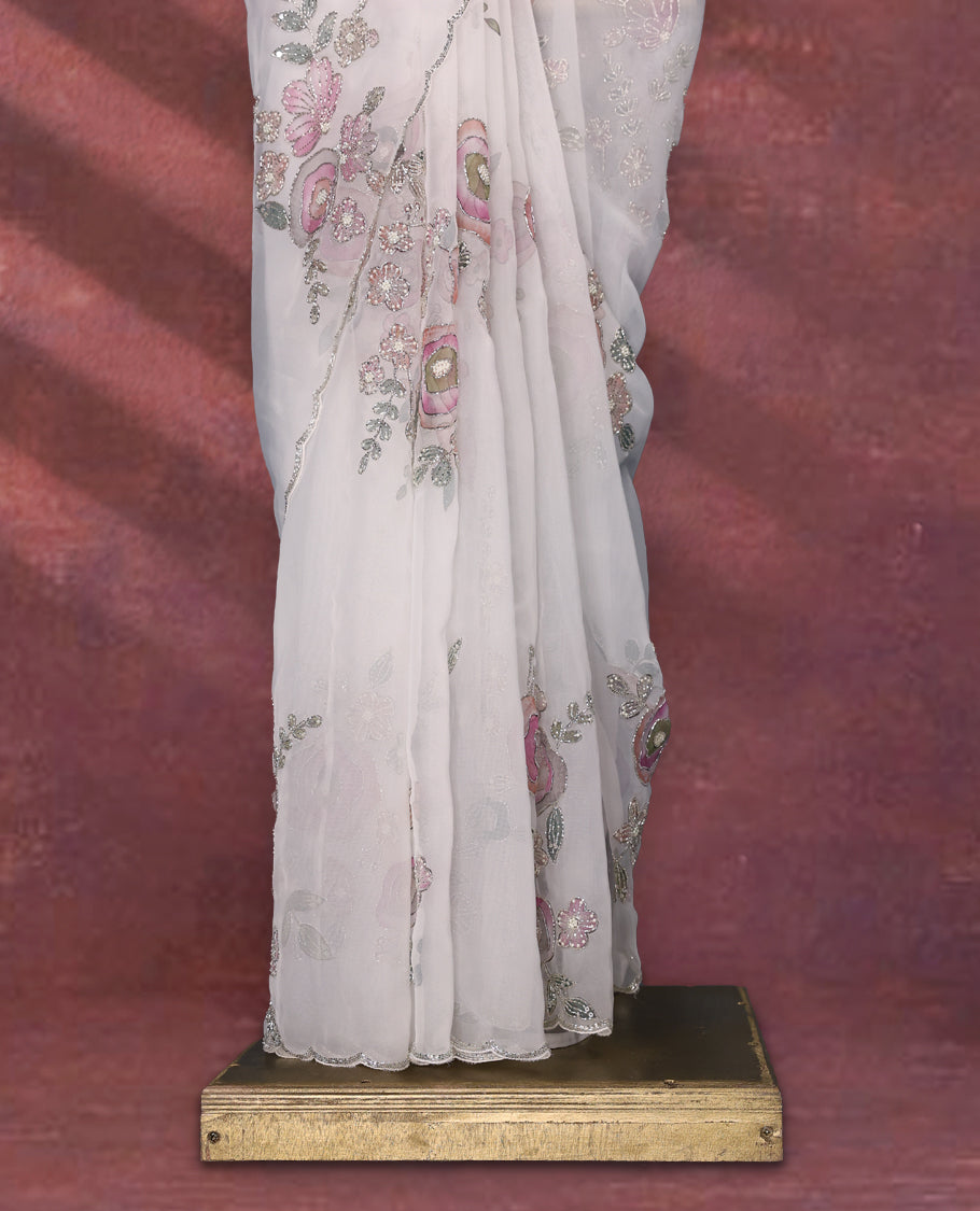 White colour pure organza saree featuring Multi Colour floral prints with intricate bead and sequin work across the body, adorned with a matching embellished border, complemented by a worked pallu and paired with a heavily worked matching blouse.