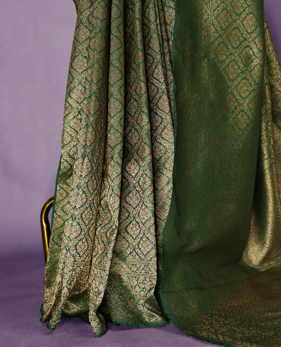 Green colour semi Banaras Katan saree featuring an antique Gold zari jacquard body, complemented by a self colour traditional border with a floral kodi design, paired with a matching blouse