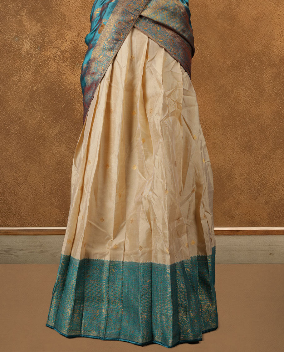Chic semi stitched dhavani in cream and teal silk with delicate zari motifs and a rich pallu &  A perfect choice for traditional celebrations, blending elegance with customizable comfort and grace.