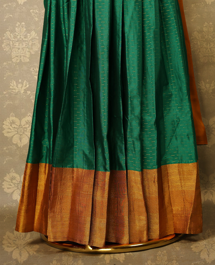 Green colour Semi Stitched  traditional half saree in semi Banarasi silk, featuring a Zari design with a Deep Orange bordered skirt. It is paired with a Rangoli georgette drape and comes with a blouse that matches the skirt’s border.