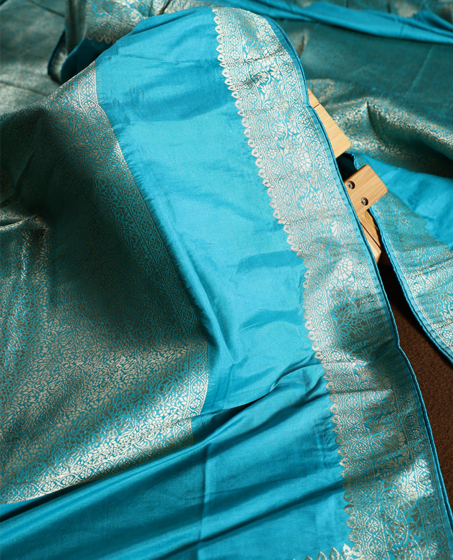 Turquoise blue colour churidhar material with elegant golden zari floral weaves and stone embellishments, paired with a plain matching bottom and dupatta.
