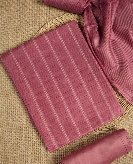 Dusty rose colour tussar suit material featuring a subtle self woven pattern and vertical lines on the body, paired with a lightweight matching dupatta with tassel edges and a plain bottom piece.