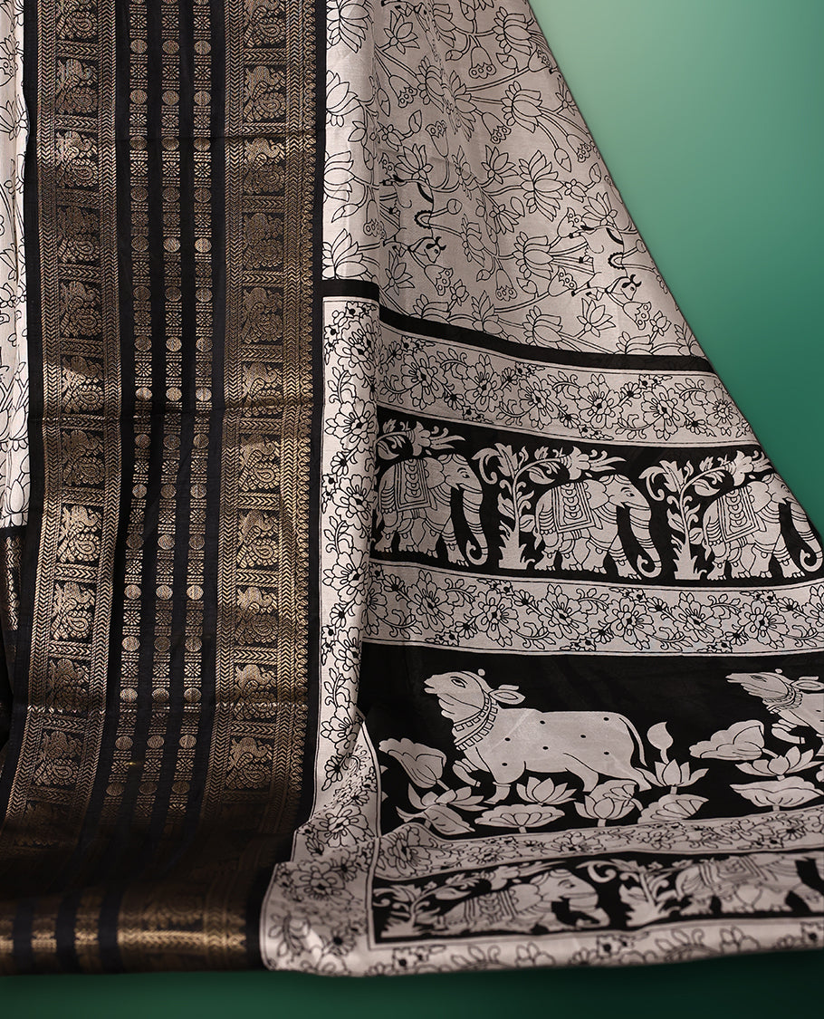 White colour saree adorned with striking black floral and cow prints across the body, enhanced by a rich black border for bold contrast, and paired with a matching blouse