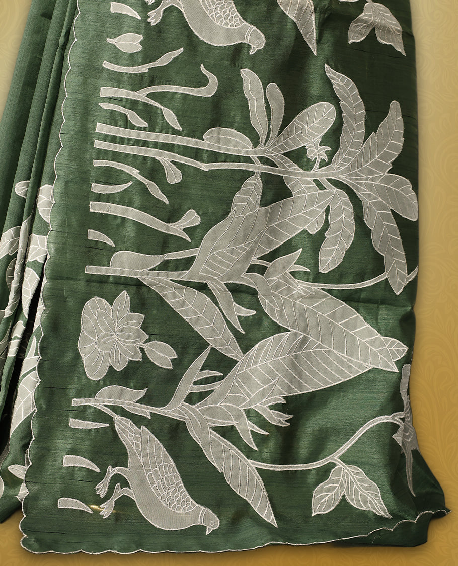 Green colour semi tussar saree adorned with elegant white applique work in leaf and floral designs across the body and border, paired with a matching blouse.