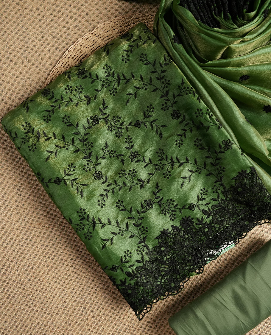 Rich Green colour dual shaded suit material with delicate black floral embroidery and lace border & Includes matching dupatta with embroidered motifs and plain bottom fabric.