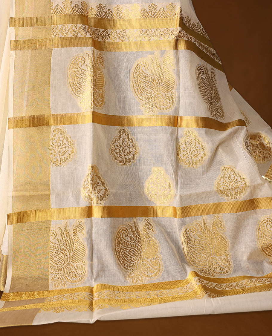 Traditional Kerala Kasavu saree in ivory with golden zari paisley motifs and a rich pallu, The graceful drape is perfect for festivals and weddings, Style with gold accessories for an elegant ethnic look.