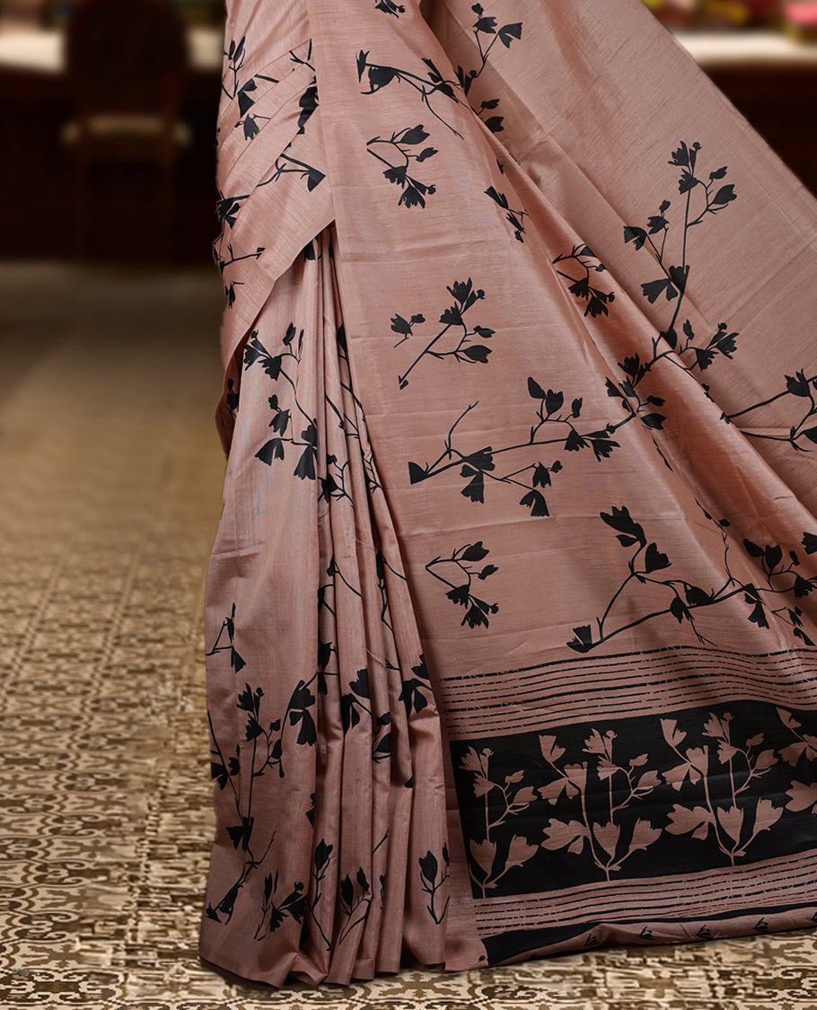 Pastel Peach colour Semi tussar silk saree adorned with black floral prints on the body and an elegant pallu & Comes with a matching blouse piece for a classy look.