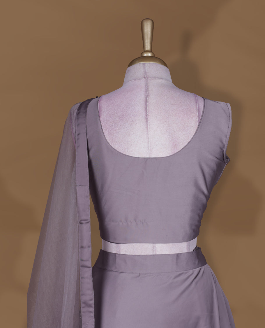 Dusty lavender colour lehenga set with stitched sleeveless blouse featuring intricate bead and sequin embroidery along the neckline and waist, paired with a matching stitched flared lehenga and plain sheer dupatta.