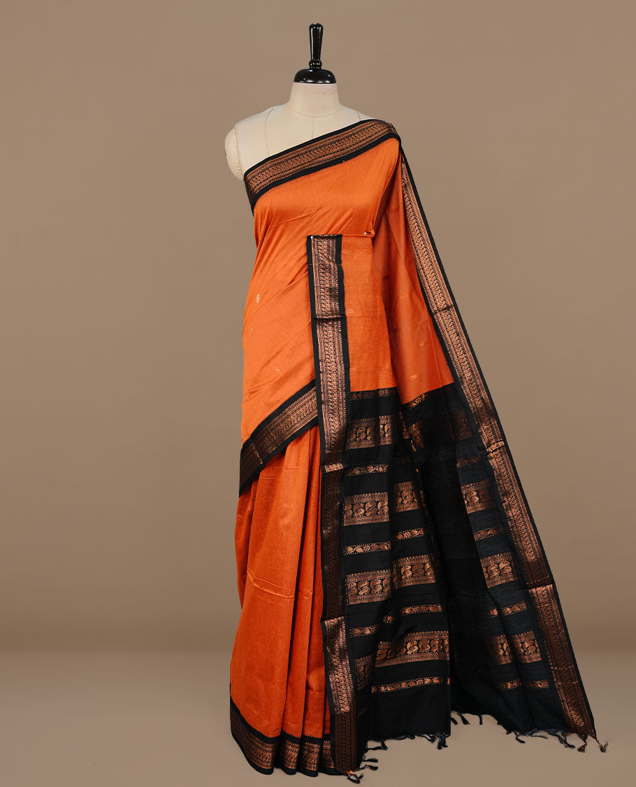 Orange colour kalyani cotton saree featuring antique zari motifs on body, complemented by black colour with Antique zari border, paired with matching blouse piece.