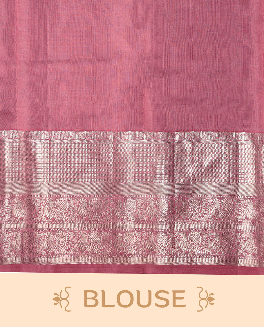 Light rose pink Colour traditional Kancheepuram silk saree adorned with antique zari small peacock motifs on the body, featuring a traditional border with light silver zari peacock and floral patterns, and paired with a matching blouse.