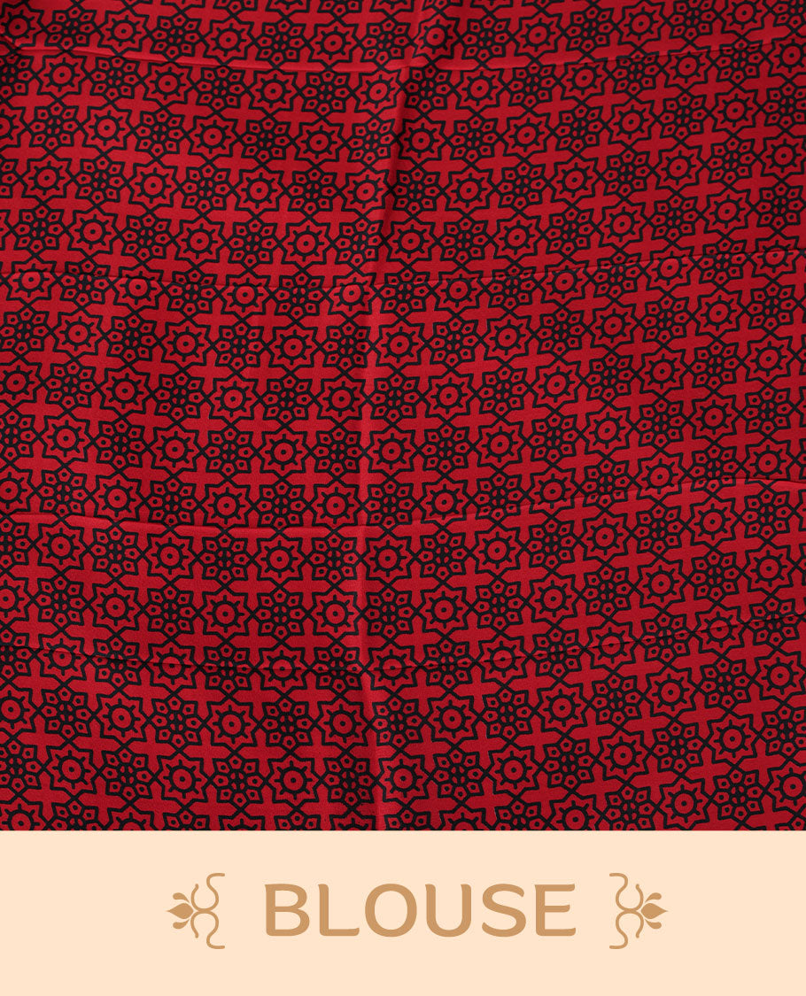 Red colour semi modal saree featuring black colour geometric borders and fine stripe detailing, finished with an oversized circular motif on the pallu, paired with a matching printed blouse.