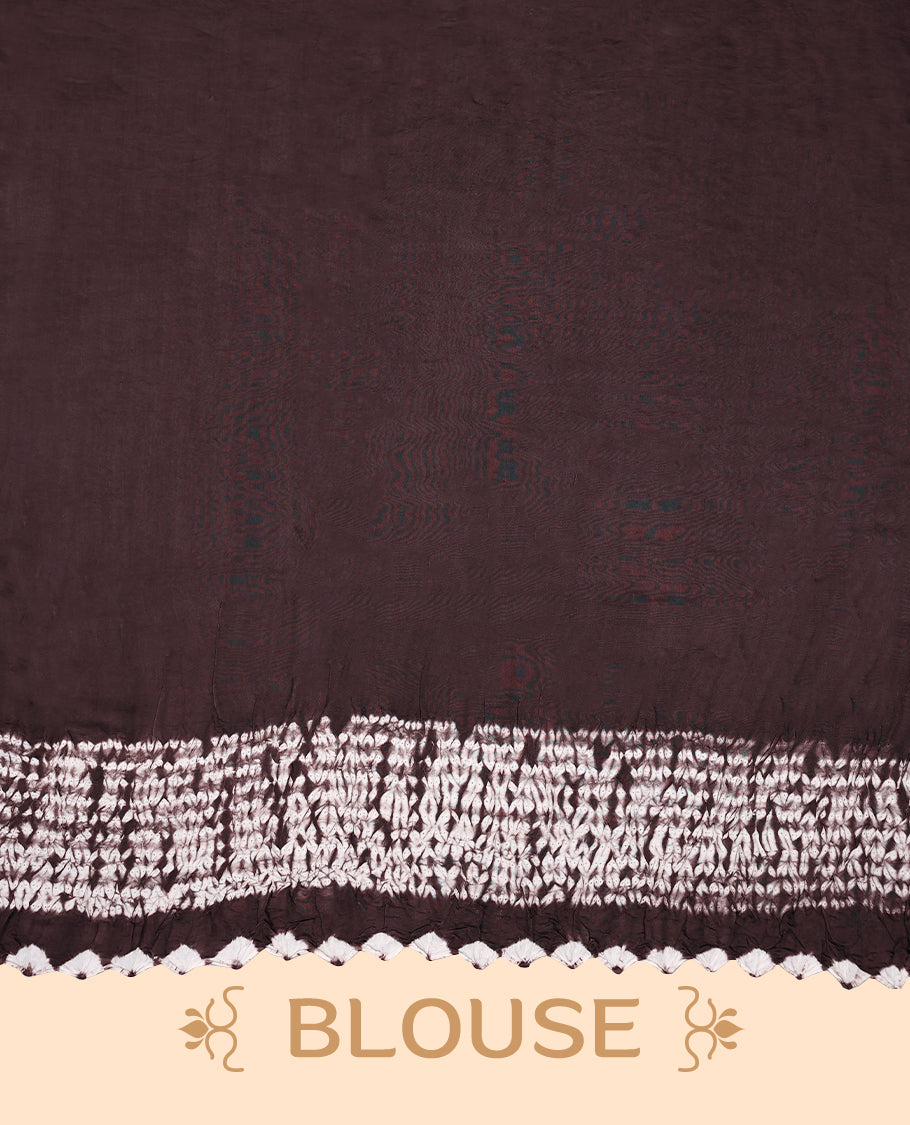 Medium coffee brown colour modal satin crepe saree featuring intricate hand done Shibori and Bandhej designs, enhanced by its smooth texture and paired with a matching blouse.