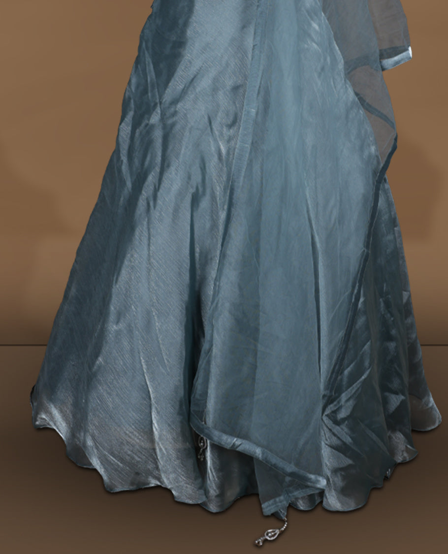 Dusty teal blue colour lehenga set with stitched sleeveless heavily embellished blouse featuring scalloped neckline, matching stitched flared lehenga, and plain sheer dupatta.